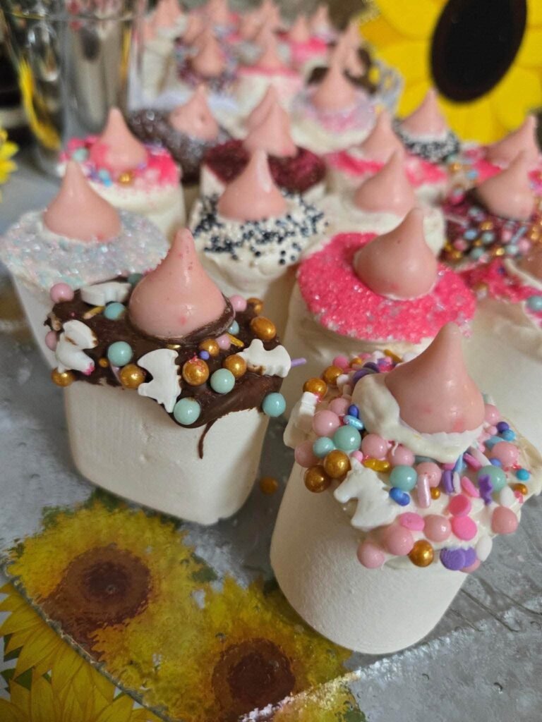 Chocolate covered baby bottle treats with pink tops and sprinkles