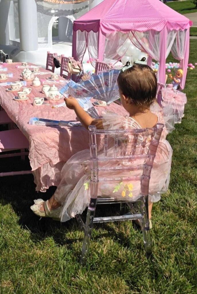 Little girl in a pink dress at a tea party table under a canopy