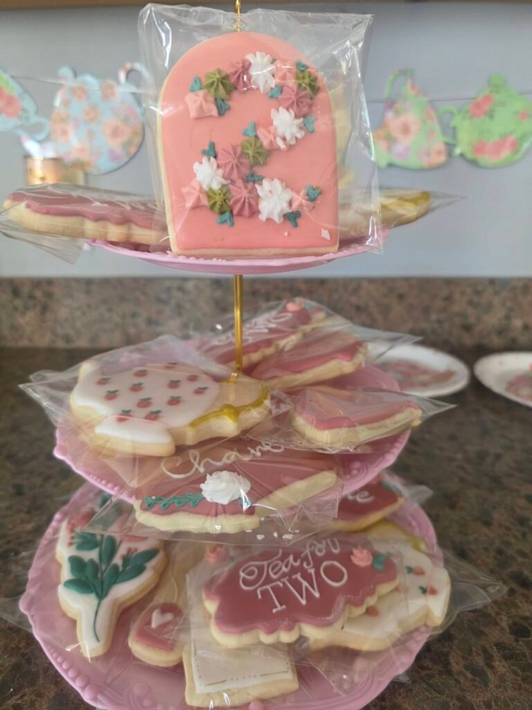Tea set cookies on a tiered stand in pink and green