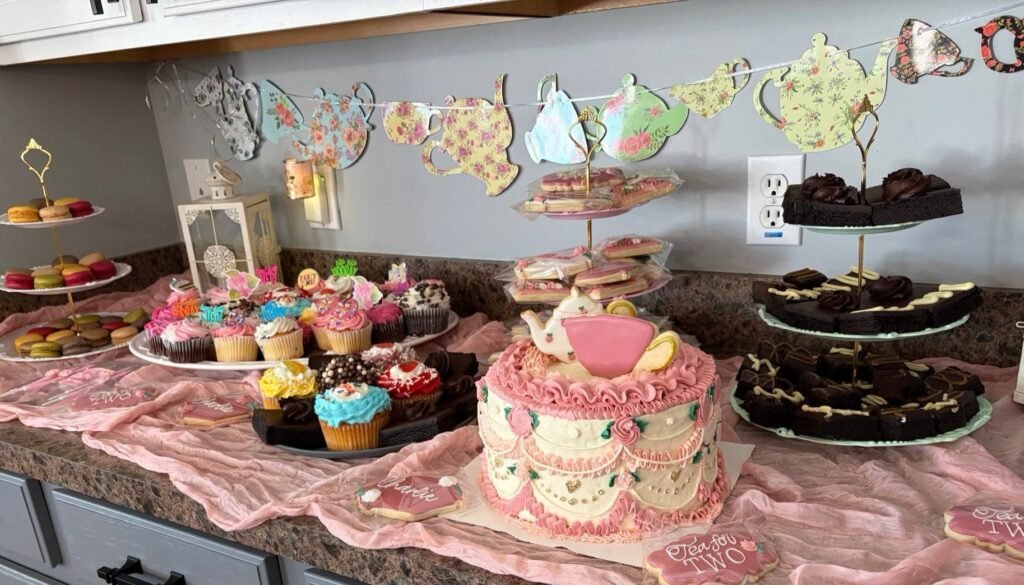 Pink dessert table with cupcakes, cookies and the teapot cake