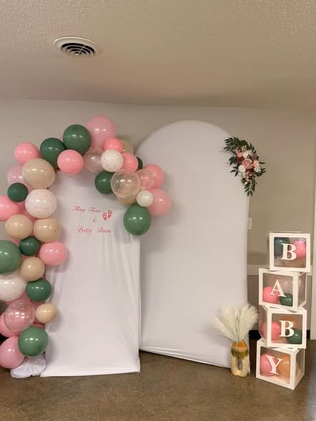 Pink, sage green and white balloon arch around white arch panels with BABY blocks