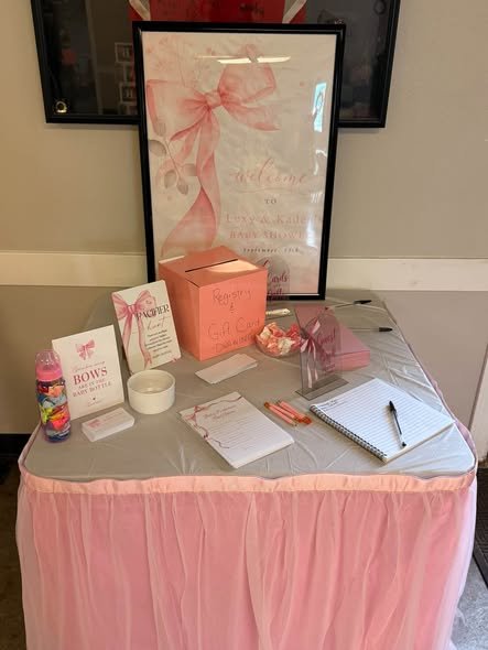 Baby shower guest book table with a pink tulle skirt, pink bow sign and card box