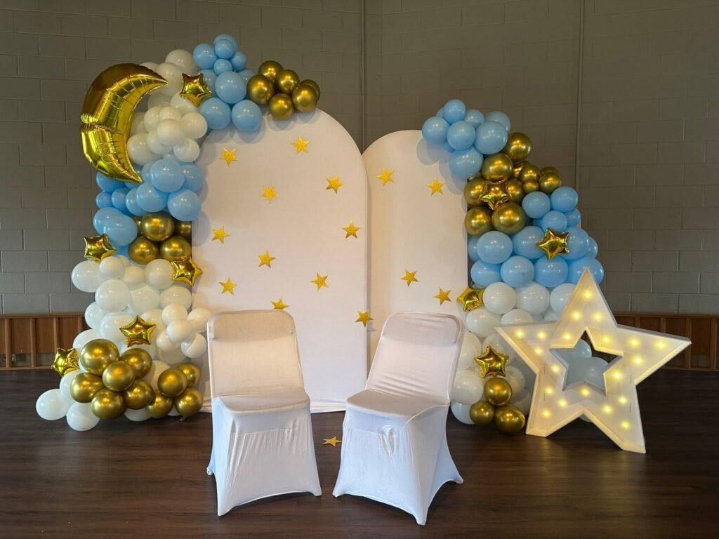 Twinkle Twinkle Little Star baby shower backdrop with a blue and gold balloon arch, star panels and a marquee star