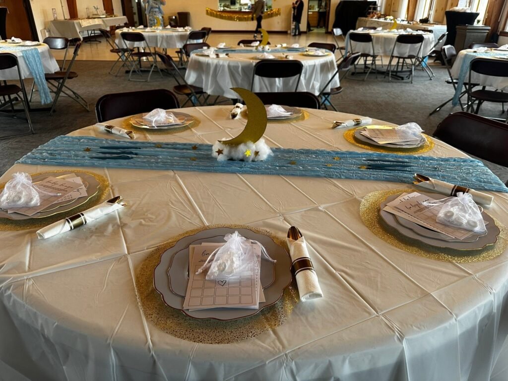Round table with a blue runner, a gold moon centerpiece and favors