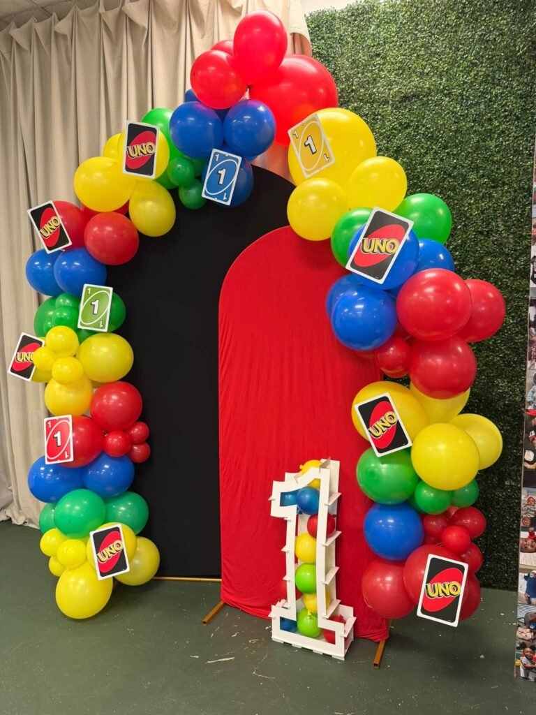 Red, yellow, green and blue balloon arch with UNO cards and a light up number 1