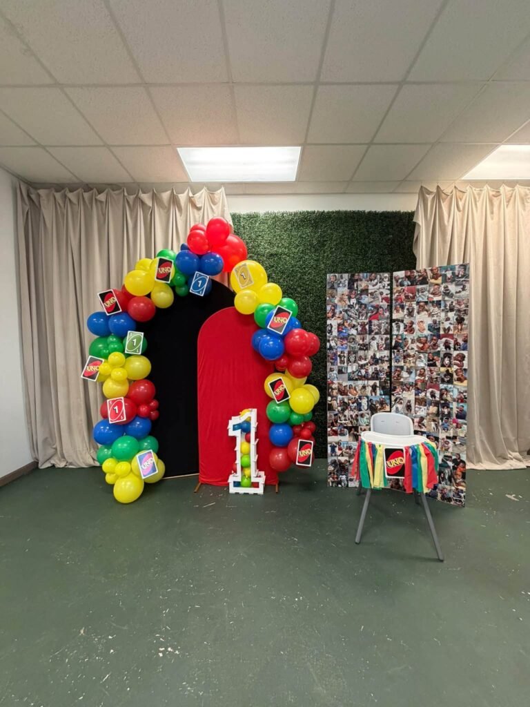 UNO balloon arch next to a photo wall in a party hall