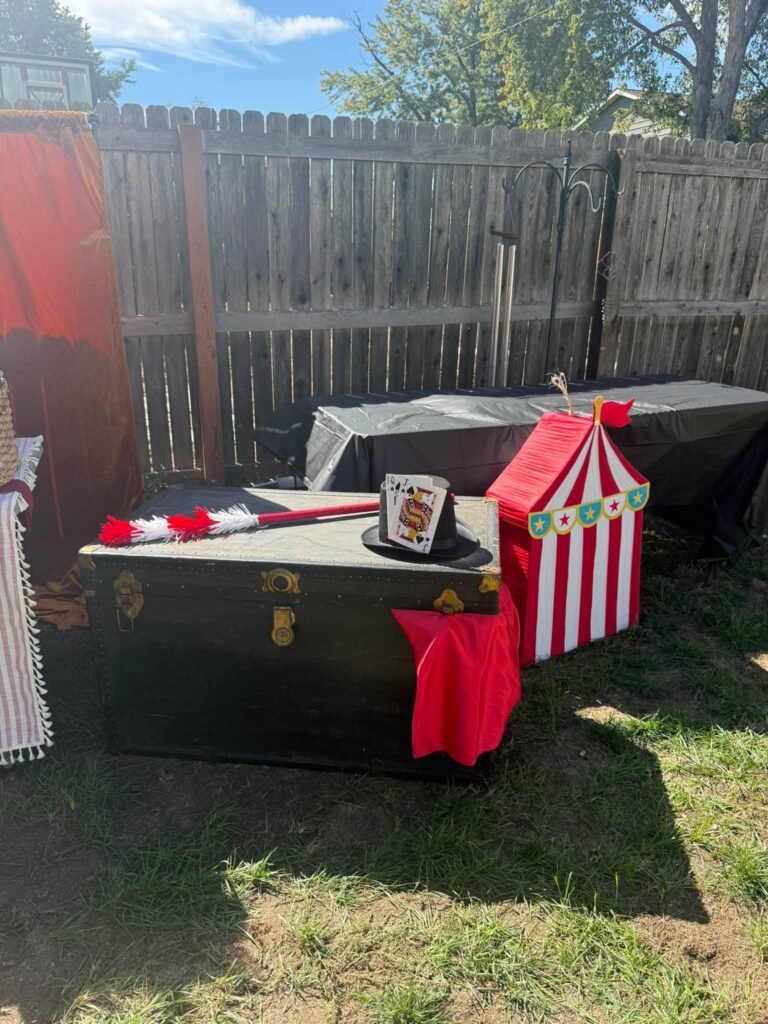 Black trunk props with a small red and white circus tent box on the lawn