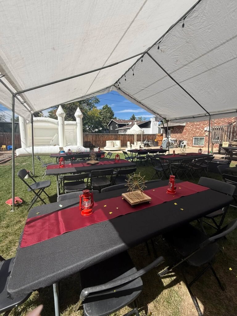 Party tent with black tables, red runners and a white bounce castle behind