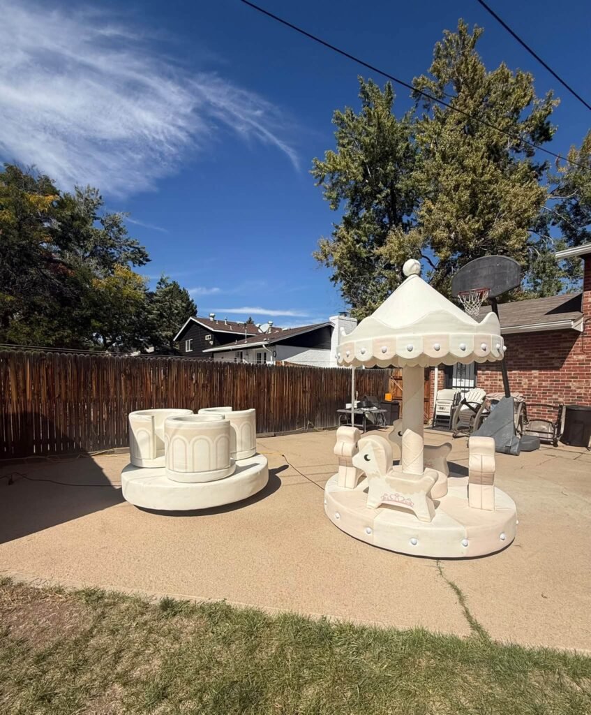 White mini carousel and teacup ride on a backyard patio