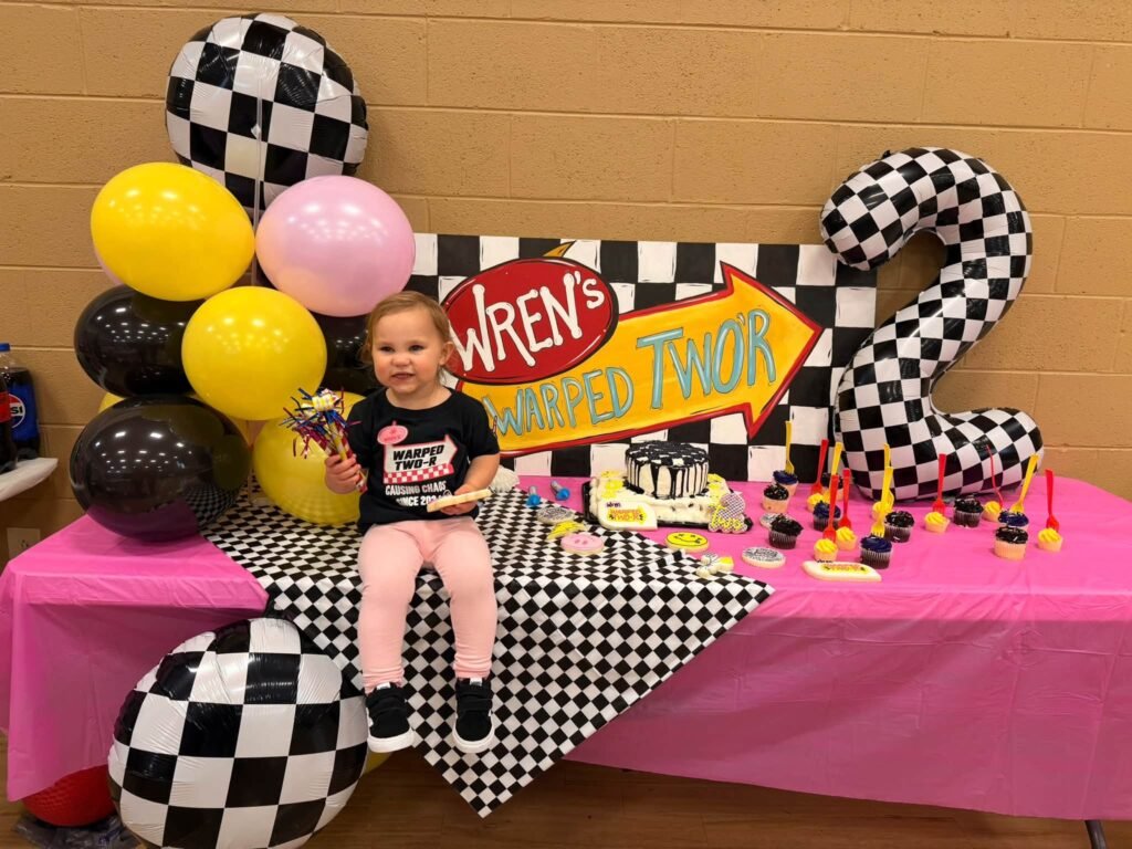 Birthday girl sitting on the table with a checkered number two