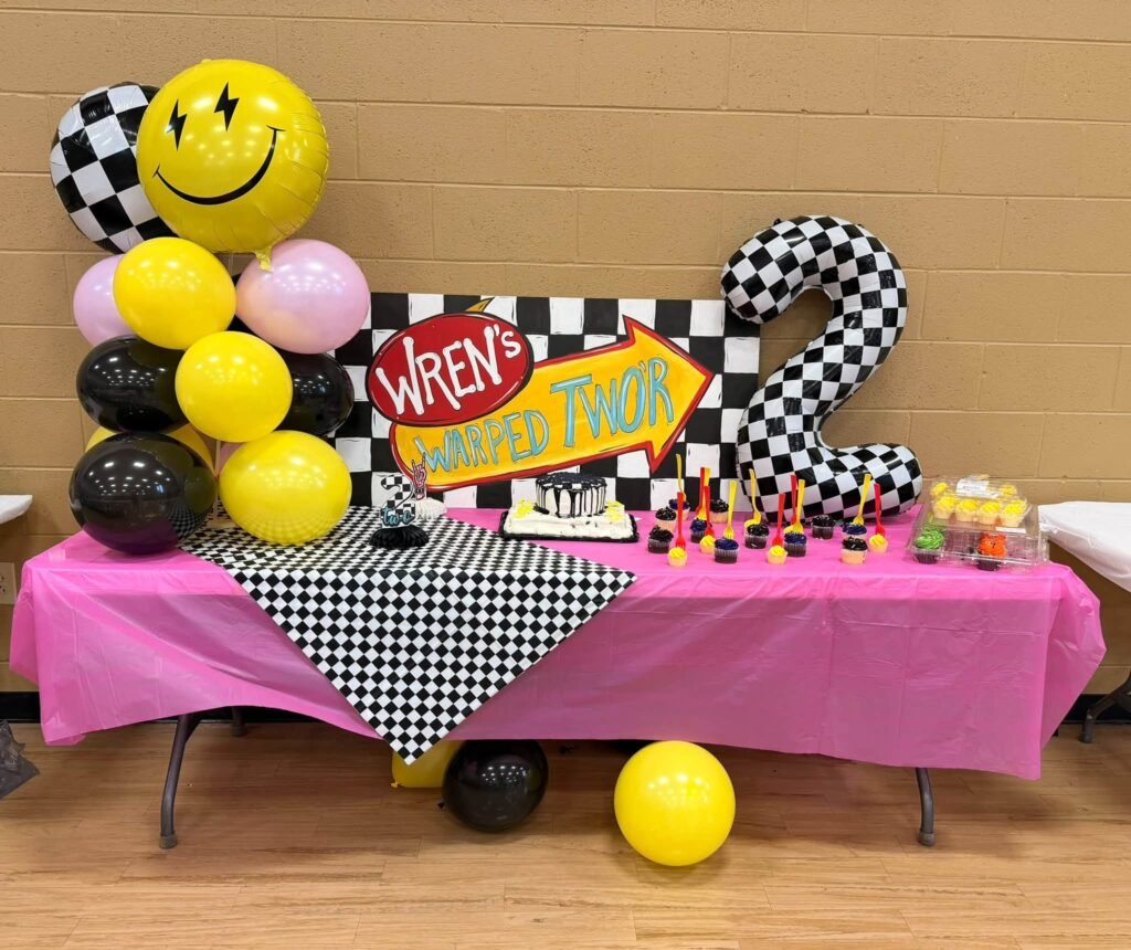 Hot pink table with smiley balloons and a Warped Two sign