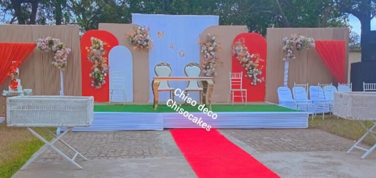 Outdoor wedding stage with floral arches and a red carpet
