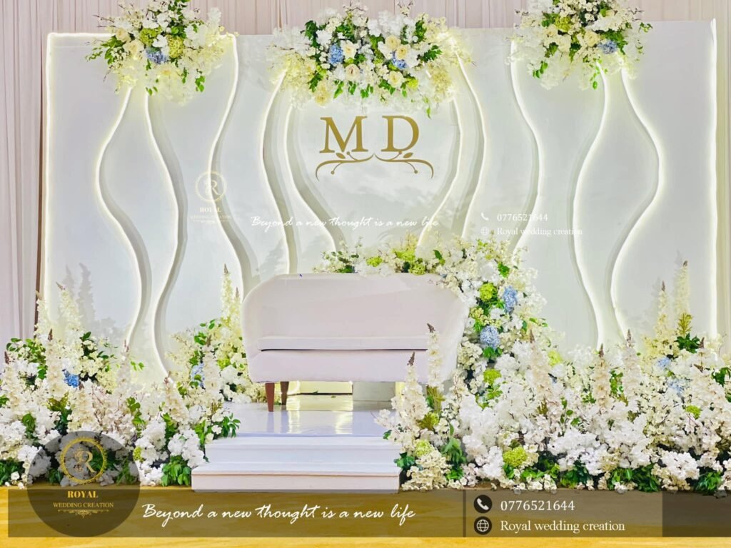 White wedding stage with couple initials, white flowers and a white sofa