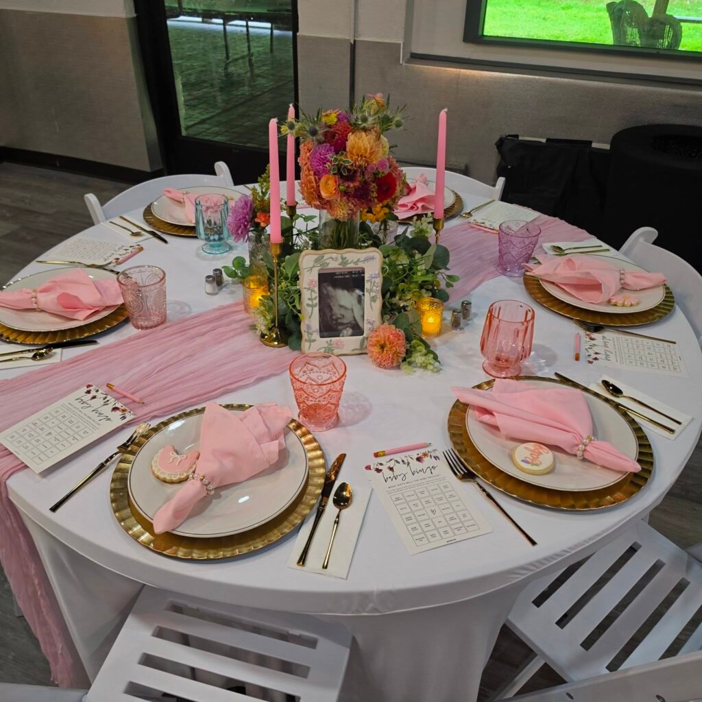 Round table setting with gold chargers, pink napkins and a flower centerpiece