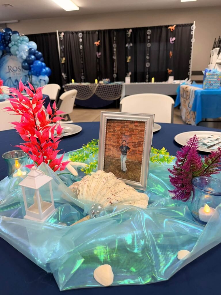 Centerpiece with red coral, shells and a lantern on blue tulle