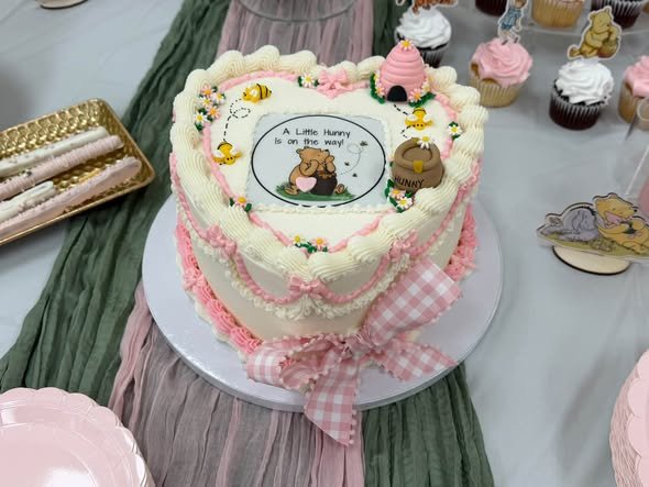 Vintage heart baby shower cake with a classic Winnie the Pooh picture and a pink gingham bow