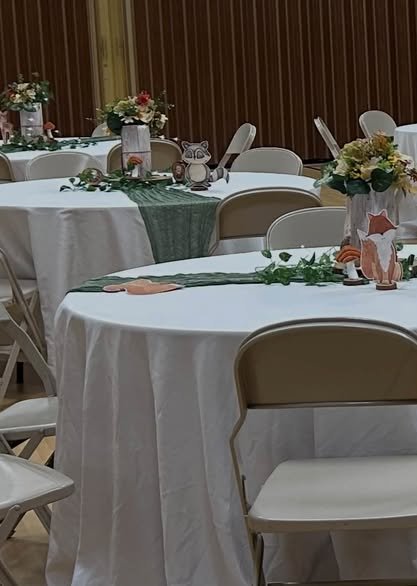Round guest tables with sage runners, ivy and small centerpieces in a hall