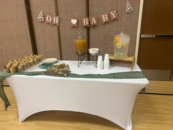Oh Baby banner over a drink station with lemonade dispensers and greenery