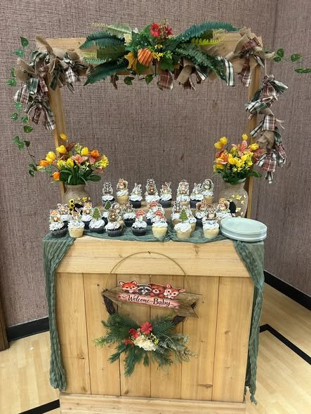 Wood dessert cart with greenery, yellow flowers and treats for a woodland baby shower