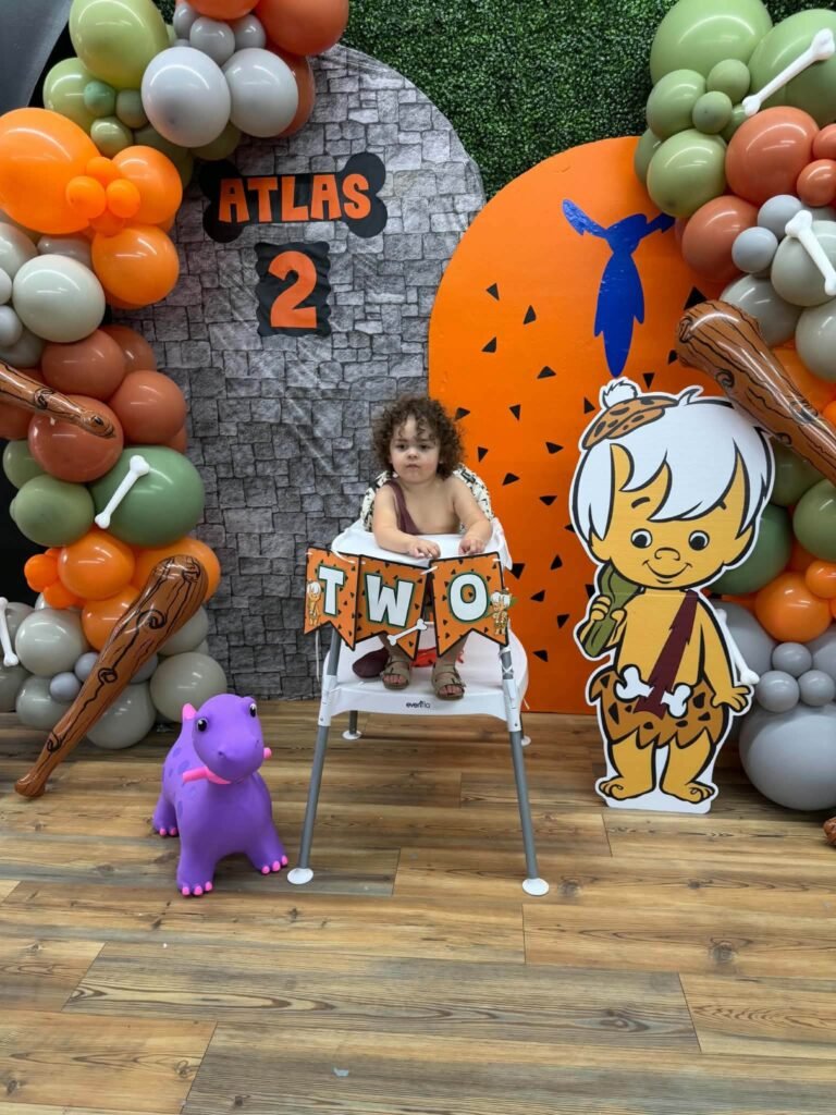 Bamm-Bamm cutout beside the backdrop and high chair